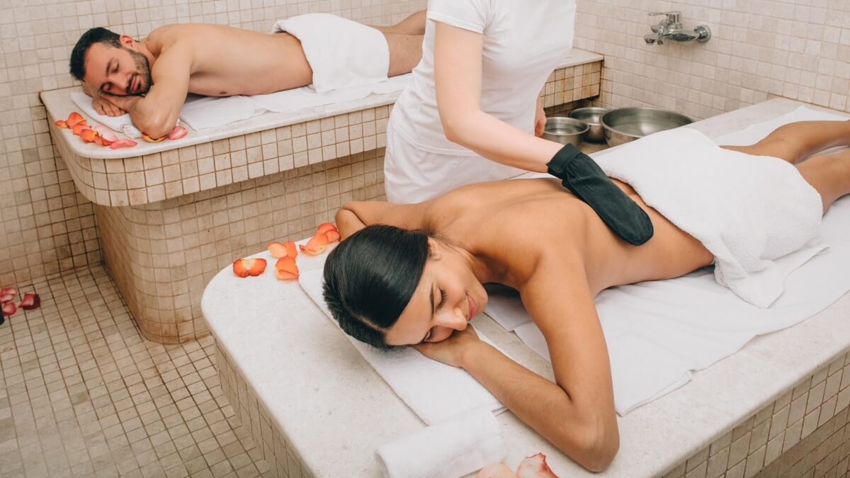 Turkiška Pirtis Hamamas (Turkish Bath Hammam). Paveiksliuke pavaizduotas gulintis vyras kuriam specialistas atlieka hamamo procedūra.
