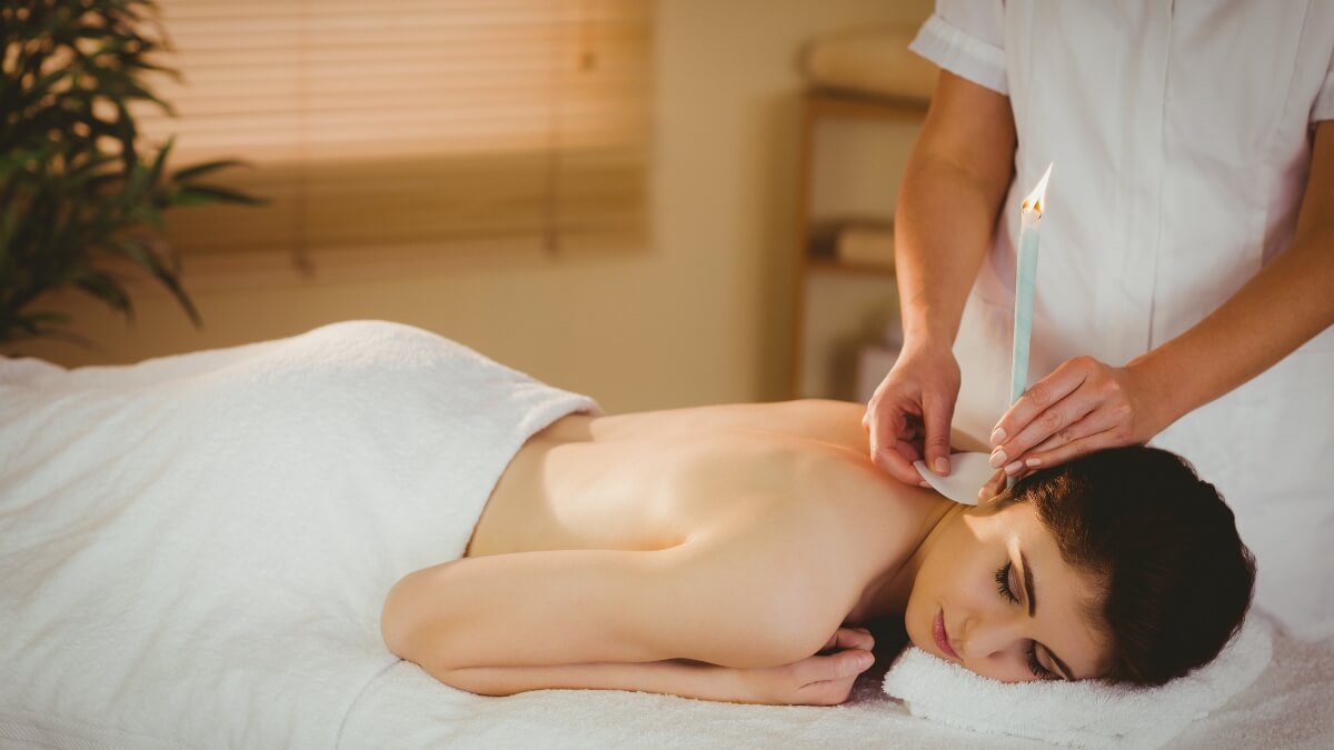 Apžvelgiama Šiluminė Ausų Terapija – arba „Ear Candling“. Iliustracijoje matome kaip specialistas taiko šilumine ausų terapiją, dar kitaip vadinama Ear Candling.