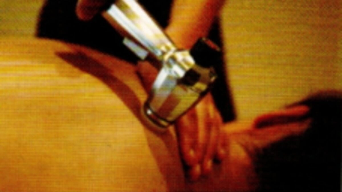 Specialistas naudoja garsinį masažo aparatą (audiosonic vibrator) ant paciento viršutinės nugaros dalies.