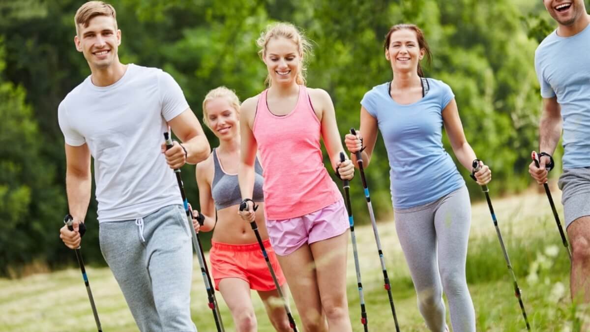Apžvelgimas šiaurietiškas ėjimas. Paveiksliuke atvaizduota grupe jaunų žmonių. Tiek vaikinų ir merginų, eidami gamtoje naudojant šiaurietiškas lazdas.