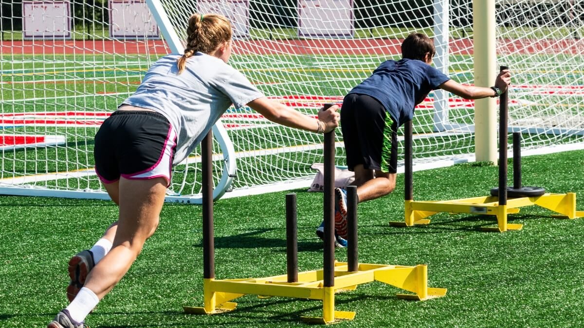Svertinių Rogių Treniruotės (Sled Training). Sportininkai sportuoja su svertinemis rogėmis lauke.