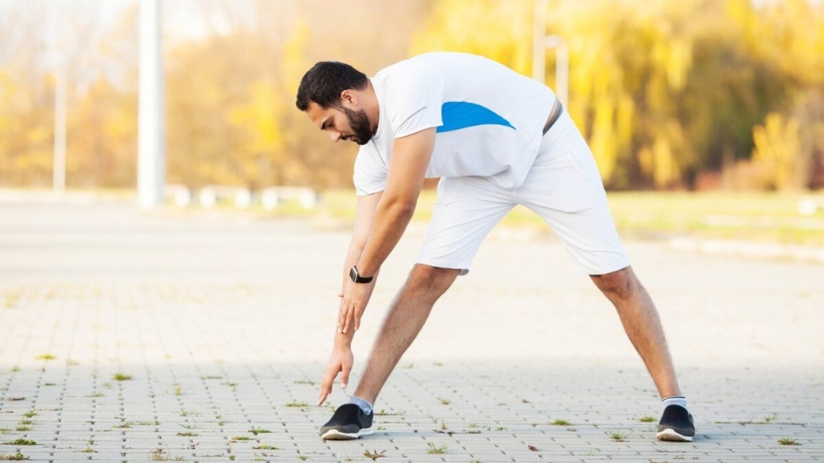 Apžvelgiami dinaminiai tempimo pratimai (dynamic stretching exercises). Pavaizduota vyro paveiksliukas kur stovėdamas siekia pirštų galus ir taip parsitempia užpakalinius kojų raumenys.