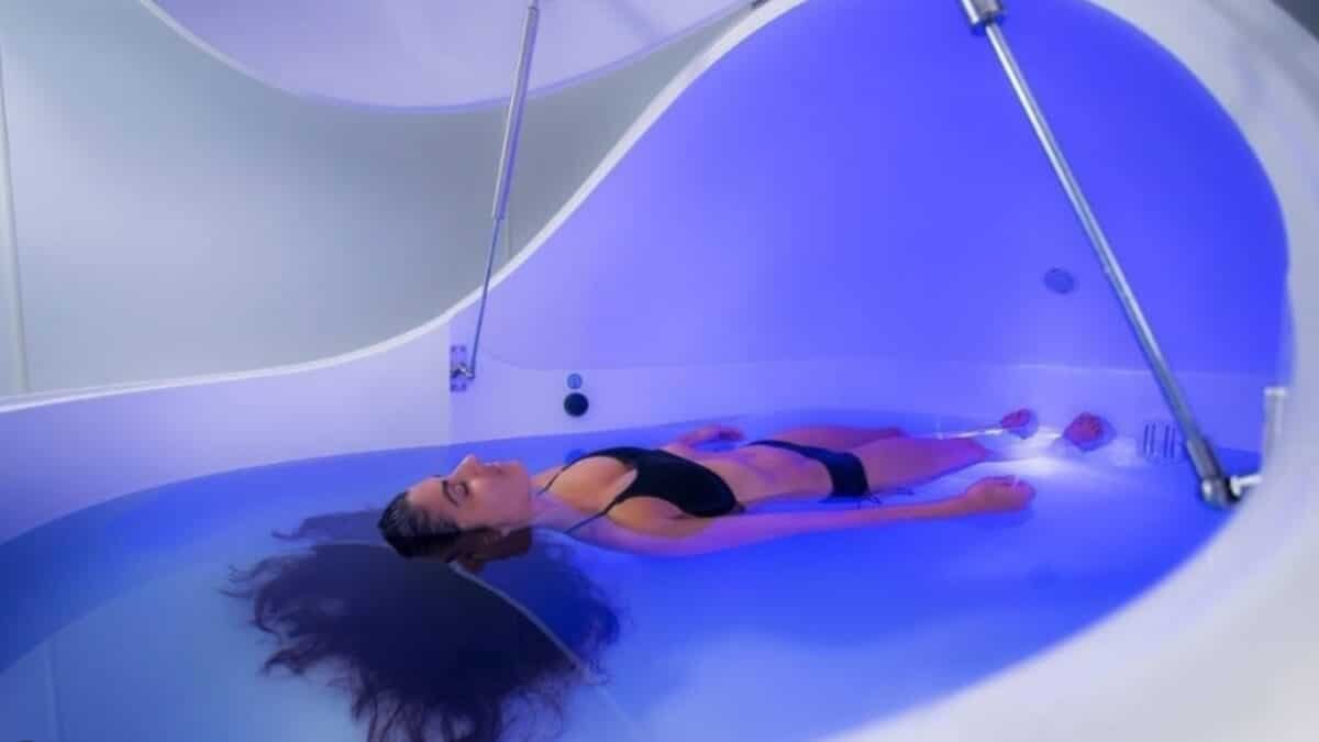 Plūduriavimo Terapija (Floatation Therapy). Moteris plūduriuoja baltoje plūduriavimo kapsulėje.