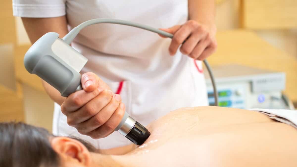Smūginės Bangos Terapija (Shockwave Therapy). Specialistė atlieka smūginės bangos procedūrą pacientui.
