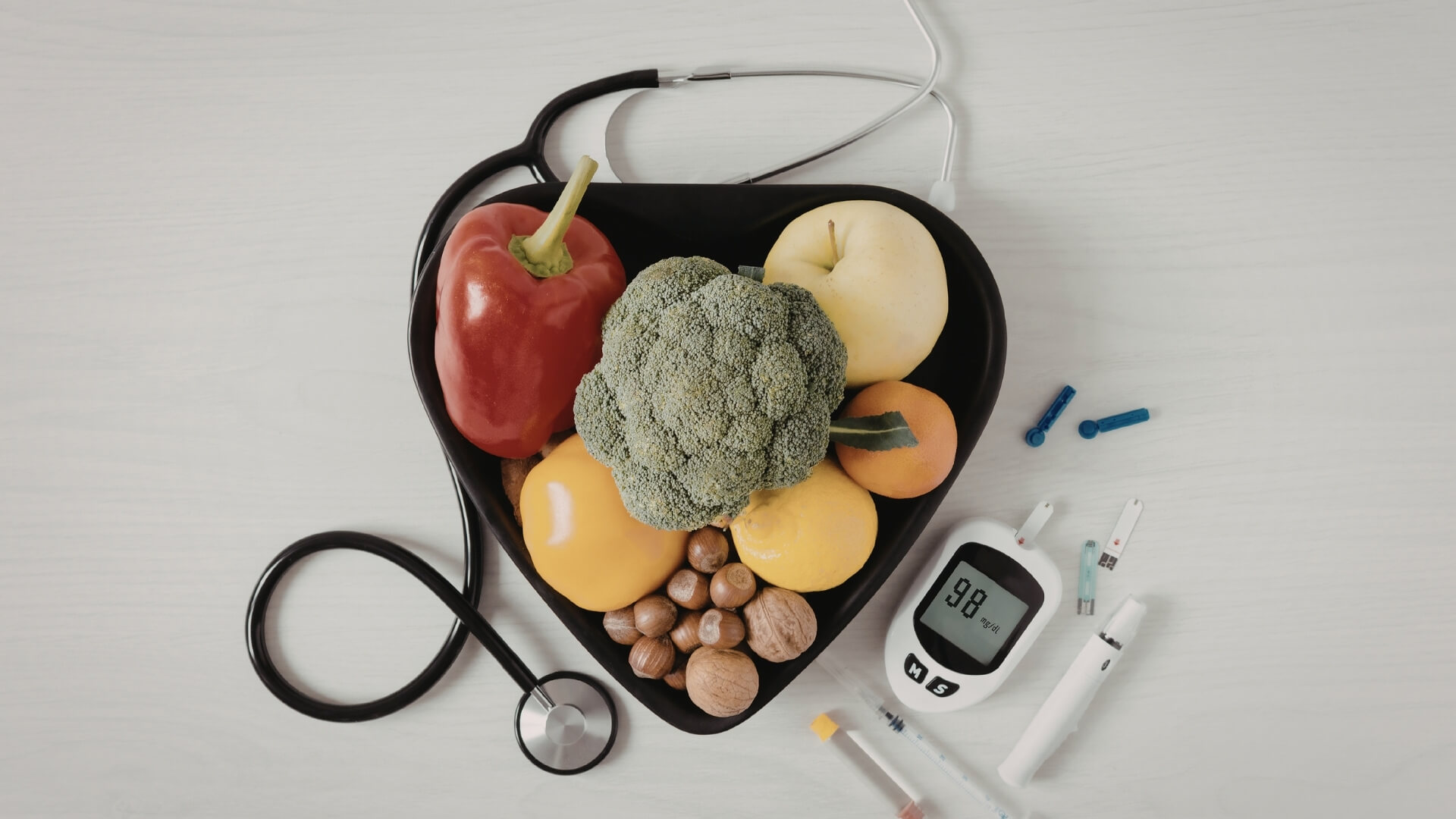 Kraujo Grupės Dieta (Blood Type Diet) Kraujo Grupės Dieta (Blood Type Diet). Širdies formos dubenyje sudėtos daržovės, vaisiai ir riešutai, šalia padėtas stetoskopas ir gliukozės matuoklis.